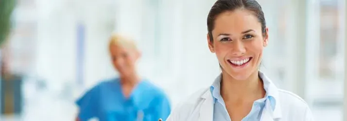 Chiropractic Komoka ON Myths Hero Female doctor smiling with an image of another hospital staff member wearing blue clothing in the background.