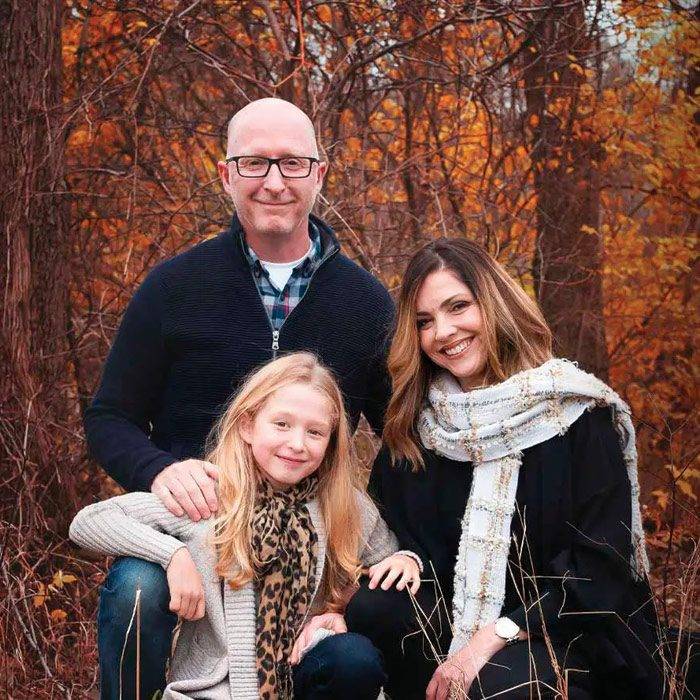 Dr. Jeff Campbell D.C. posing with his family, all smiling with a background of trees in autumn tones.